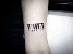 a black and white photo of a wrist with piano keys on it's side