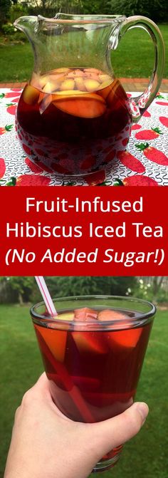 a hand holding a glass cup filled with fruit - infused hibiscus iced tea