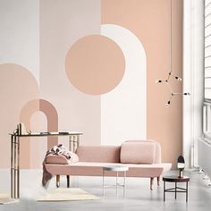 a living room with a pink couch and white rugs on the floor in front of a large wall mural