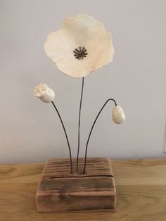 a white flower sitting on top of a wooden block