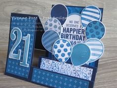 a happy 21st birthday card with blue and white balloons in the center, on a wooden table