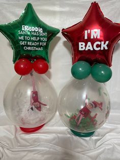 two christmas decorations in glass vases with red and green foil stars on the top