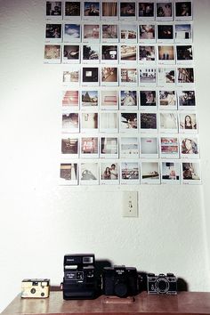 several polaroid cameras sitting on top of a wooden table in front of a wall