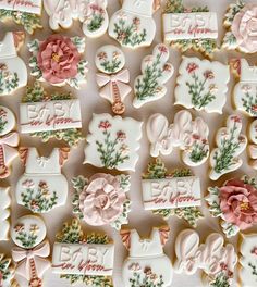 many decorated cookies are displayed on a white tablecloth with pink trimmings and flowers