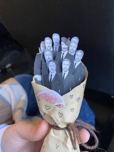 a person holding up a bunch of paper with pictures on it and tied in twine