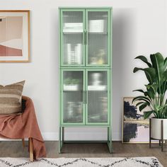 a green cabinet sitting next to a plant in a living room