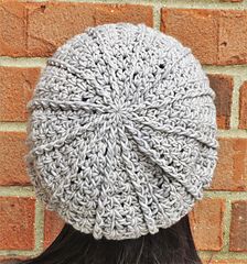 a close up of a person wearing a knitted beanie against a brick wall