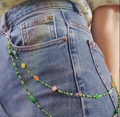 a woman's jeans are adorned with beaded beads and green glass beads as she stands in front of the camera