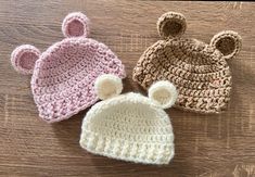 three crocheted hats sitting on top of a wooden table