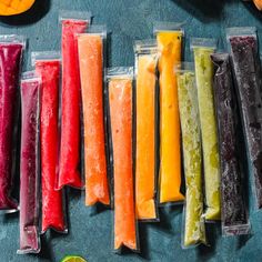 several different colored candles are lined up on a table next to oranges and lime slices