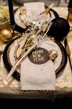 a black and gold new year's eve table setting with napkins, silverware, and golden decorations