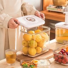 a woman is holding a container full of fruit on a table with other food items