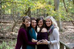 three women hugging each other on a bridge in the woods