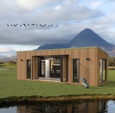 a small wooden building sitting on top of a lush green field next to a lake