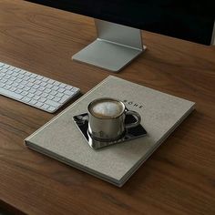 a cup of coffee sitting on top of a book next to a keyboard and mouse