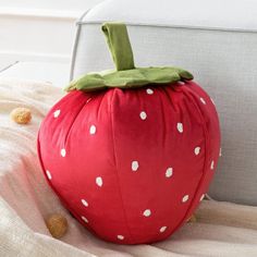 a stuffed strawberry sitting on top of a white couch next to a pillow with polka dots