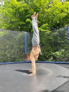 a person doing a handstand on a trampoline