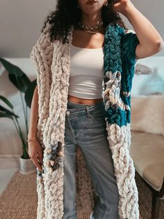 a woman standing in front of a couch wearing a white tank top and blue crocheted scarf