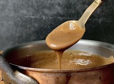 a wooden spoon pouring liquid into a pot