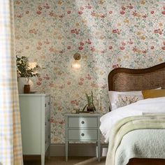 a bedroom with floral wallpaper and an old fashioned dresser in front of the bed