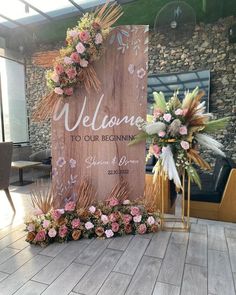 a welcome sign with flowers and greenery on it