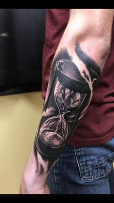 a man with a tattoo on his arm holding an hourglass