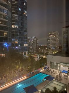 an aerial view of a city at night with buildings in the background and pool lit up