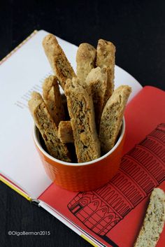 a small bowl filled with bread sticks on top of a book next to a sandwich