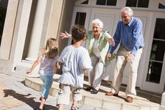 an older man and two young children are walking towards the front door of a house