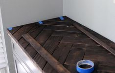 a blue bucket sitting on top of a wooden floor next to a white wall with shutters