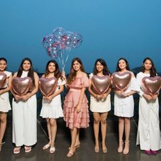 a group of women standing next to each other holding heart shaped balloons