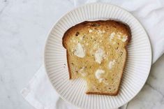 a piece of bread on a paper plate with some butter spread on it, sitting on a marble surface