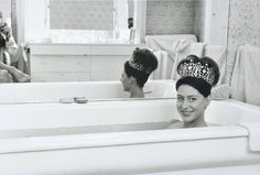 two women in bath tubs with towels on the side and one woman wearing a tiara