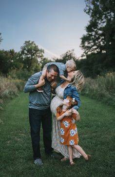 a man and two women hugging their children in the grass