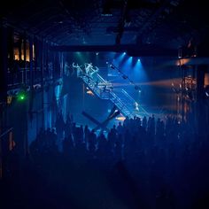 a crowd of people standing in front of a stage with lights on it's sides