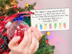 a person holding a christmas ornament in front of a tree