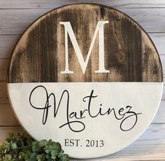 a wooden sign with the word'm'on it and a plant next to it