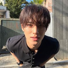 a young man is posing for the camera in front of a fenced area with his hands on his hips