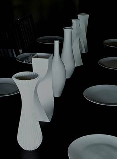 several white vases and plates on a black table with one empty plate in the middle