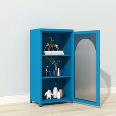 a blue bookcase with shelves and vases on it in front of a white wall