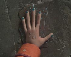 a person's hand with blue and white nail polish on it next to a rock