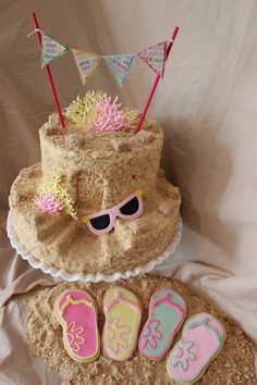 a cake that has been decorated with flip flops and sunglasses on it, next to some cookies