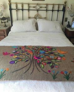 a bed with an embroidered tree on it