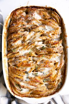 a casserole dish with meat and cheese in it on a striped cloth, ready to be eaten