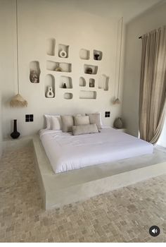 a large bed sitting in the middle of a bedroom next to a wall with shelves on it