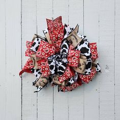 a red and black cow print hair bow on a white wooden background with the word love written across it