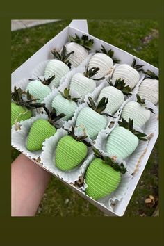 a box filled with green and white cupcakes on top of a grass covered field