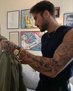 a man with tattoos on his arm looking at a shirt