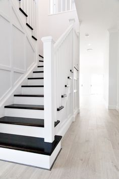 a white staircase with black railing and handrails leading up to the second floor