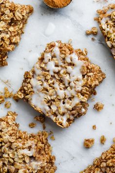 granola bars with white icing on top and spoon next to them, sitting on a marble surface